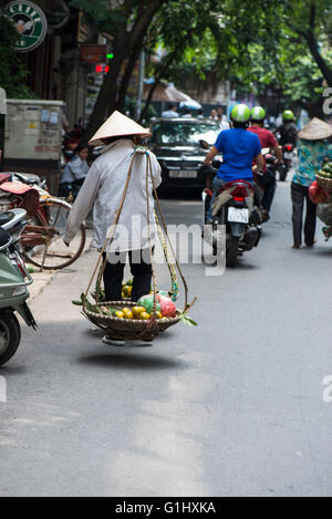 Donna vietnamita che porta frutto in cesti, Old Hanoi Foto Stock