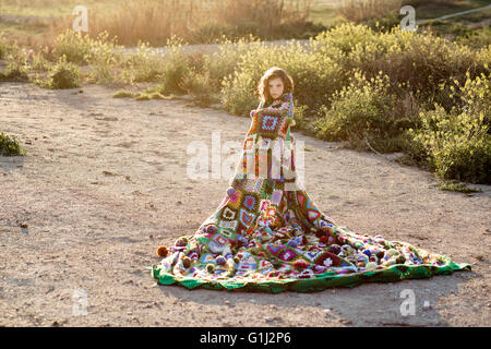 Ragazza avvolto in una coperta in piedi in un campo Foto Stock