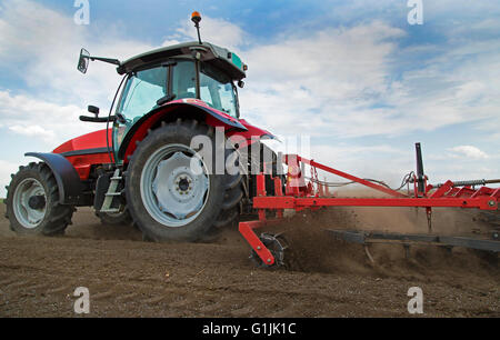 Close-up di griculture trattore rosso campo coltivato oltre il cielo blu Foto Stock