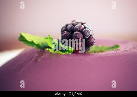 Primo piano su un viola jelly pudding con un Blackberry e foglie di menta Foto Stock