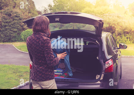 Una giovane donna è l'apertura del tronco di un automobile Foto Stock