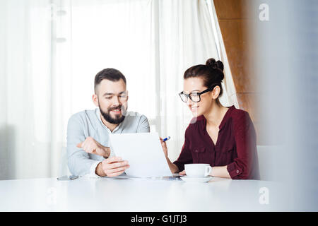 Due lieti attraente giovani imprenditori seduto e a discutere di nuovo progetto nella sala riunioni Foto Stock