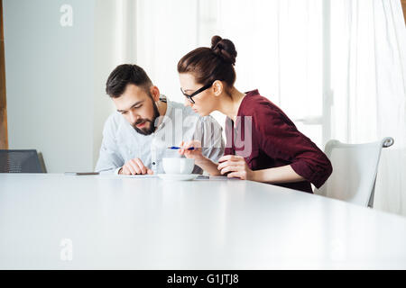 Concentrato di due giovani imprenditori che lavorano insieme sulla riunione in ufficio Foto Stock
