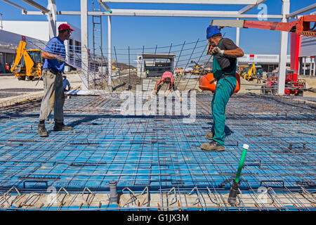 Lavoratori edili installazione di rete di rinforzo al cantiere. Foto Stock