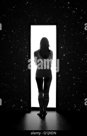 Donna entra per uno spazio bianco da scuro con stelle, immagine monocromatica Foto Stock