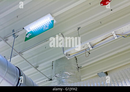 Soffitto con tubi di ventilazione per l'aria condizionata e fire exit segno. Foto Stock