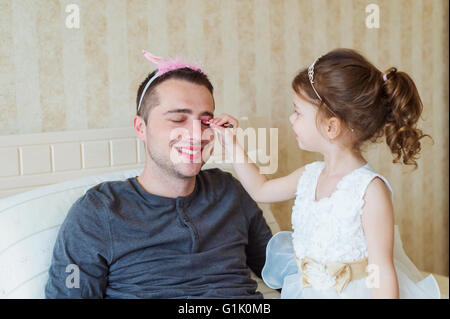 Ragazza carina mettendo su make up sul suo padre Foto Stock