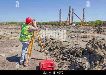 La donna è di rilevazione del livello di misurazione sul sito in costruzione. Geometri garantire misurazioni precise. Foto Stock