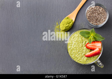 Tè verde Matcha chia budino di sementi, dessert con menta fresca e fragola su un nero ardesia background sana colazione Foto Stock