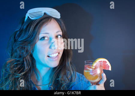 Giovane donna avente un cocktail al partito Foto Stock