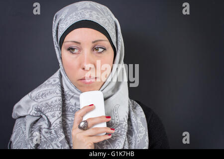 Bella donna musulmana in hijab in possesso di un telefono cellulare Foto Stock