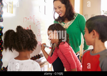 Pupillo la scrittura sulla scheda presso la scuola elementare di classe di matematica Foto Stock