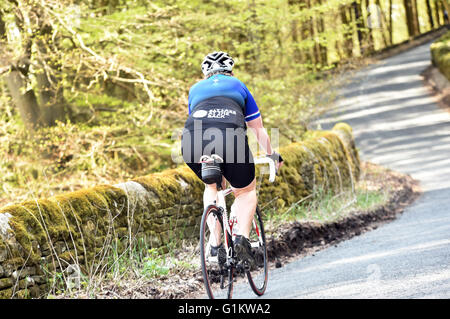 Donna sovrappeso ciclista in sella fino alla cima di una collina su un sportivi, Yorkshire Foto Stock