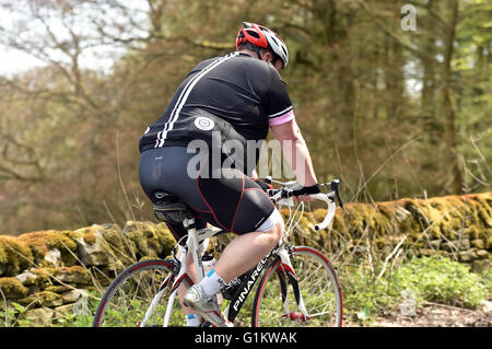 Il sovrappeso ciclista in sella fino alla cima di una collina su un sportivi, Yorkshire Foto Stock