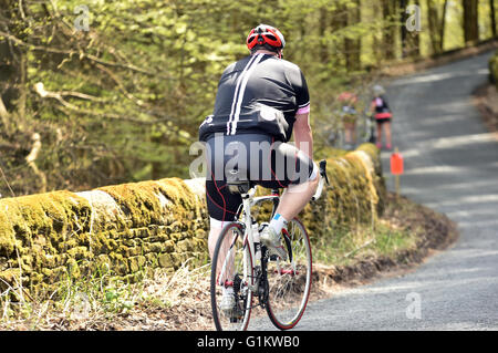 Uomo sovrappeso ciclista in sella fino alla cima di una collina su un sportivi, Yorkshire Foto Stock