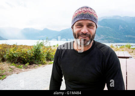 Uomo sorridente indossando beanie hat all'aperto Foto Stock