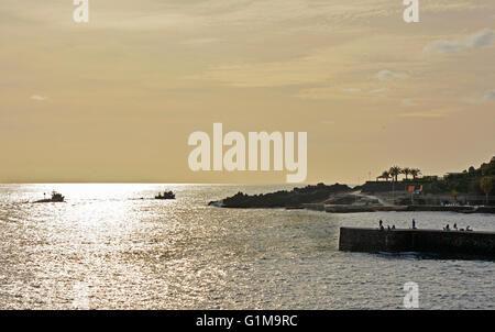 Tramonto sull'Oceano Atlantico dalla zona lido di Funchal in Madeira, Portogallo. Con barche da pesca e Ponta Gorda. Persone fishin Foto Stock