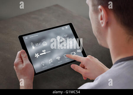 L'uomo utilizza Applicazione per smart home control sul tablet. Interno del soggiorno in background. Foto Stock