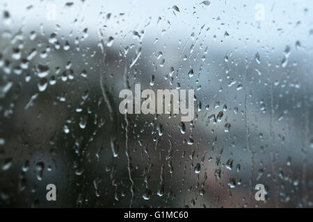 Una chiusura di gocce di pioggia gocciolare una finestra su un wet Rainy day Foto Stock