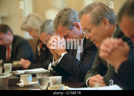 Il Presidente degli Stati Uniti George Bush china il capo come Segretario della Difesa Donald Rumsfeld, destra, dice una preghiera prima di iniziare una riunione del gabinetto nel Cabinet Room della casa bianca Settembre 14, 2001 a Washington, DC. Questa è stata la prima riunione del cabinet completo a seguito degli attentati terroristici su settembre 11th. Foto Stock