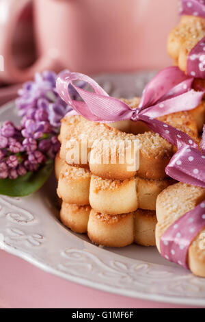 I cookie con nastri rosa su una piastra bianca con fiori lilla Foto Stock