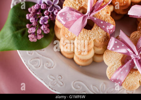 I cookie con nastri rosa su una piastra bianca con fiori lilla Foto Stock