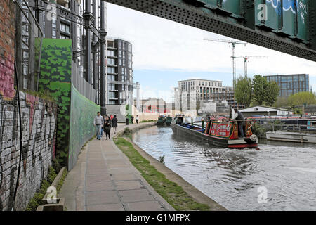 La gente camminare passato barca sul Regents Canal alzaia vicino Gasholders Appartamenti e parco in Kings Cross Londra UK KATHY DEWITT Foto Stock