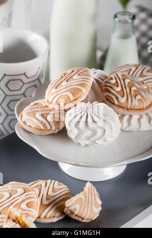 I cookie su bianco e grigio con piastra di tazze di caffè e bottiglie di latte bianco su sfondo serrande Foto Stock