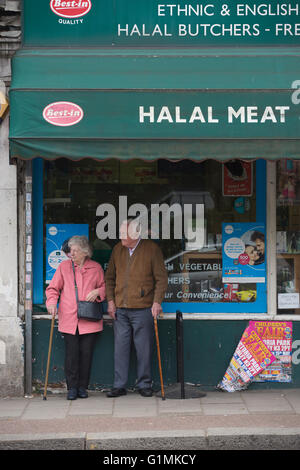 Coppia di anziani si fermò al di fuori di una carne halal & pollame macellai shop, finchley central, a nord di Londra, England, Regno Unito Foto Stock