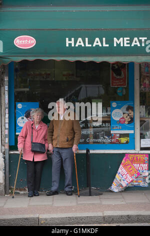 Coppia di anziani si fermò al di fuori di una carne halal & pollame macellai shop, finchley central, a nord di Londra, England, Regno Unito Foto Stock