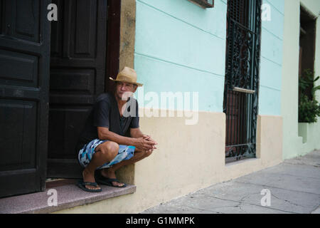 Uomo che indossa cappello di Panama è seduto sulla porta di casa a Santiago de Cuba, Cuba. Foto Stock