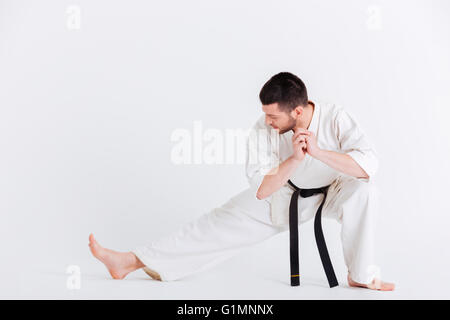 Giovane uomo in kimono stretching isolato su uno sfondo bianco Foto Stock