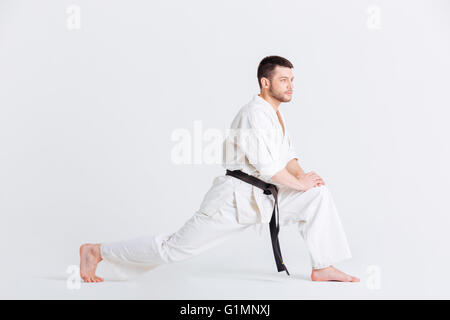 Uomo in kimono in fase di riscaldamento isolato su uno sfondo bianco Foto Stock