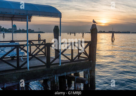 Jetty sull'isola del Lido al tramonto, Venezia in background Foto Stock