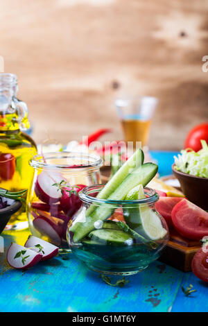 Gli ortaggi biologici sul tavolo rustico. Fette di cetriolo. Ingredienti per insalata. Cibo vegetariano, concept Foto Stock