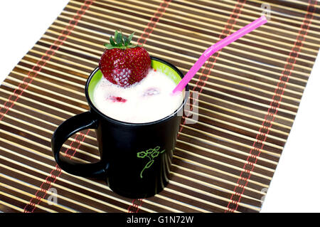 Cocktail di latte in una tazza nera, è decorato con fragola Foto Stock