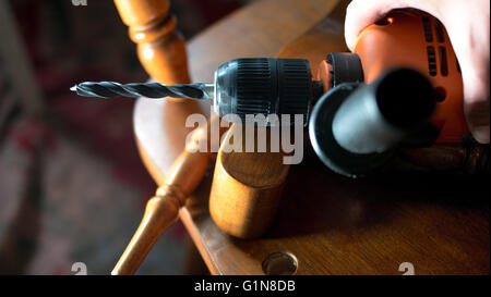 La riparazione della sedia in legno con trapano close up, pezzi di legno lucidato e praticare con il bit installato sopra al di sopra della vista Foto Stock