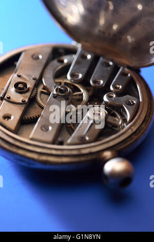 Il vecchio orologio da tasca posteriore con meccanismo aperto su sfondo blu Foto Stock