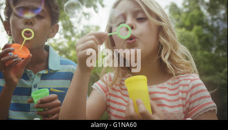 Bambini che giocano con la bacchetta di bolla nel parco Foto Stock