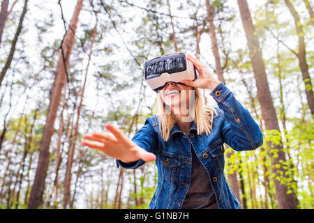 Donna che indossa la realtà virtuale gli occhiali di protezione al di fuori in primavera la natura Foto Stock