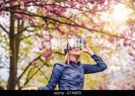 Donna che indossa la realtà virtuale gli occhiali di protezione al di fuori in primavera la natura Foto Stock