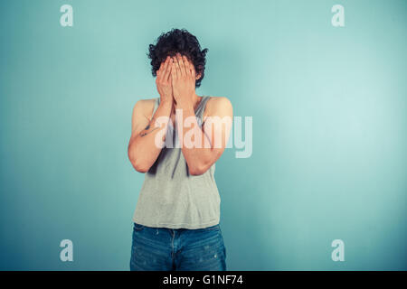 Un giovane uomo tiene il suo volto nel suo palms Foto Stock