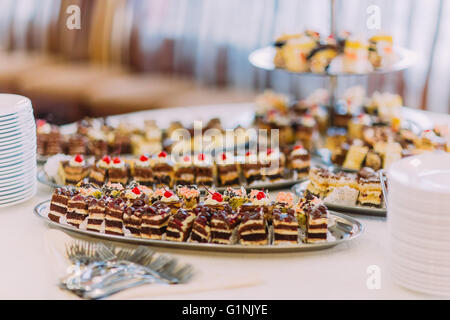 Vista da vicino la raccolta di deliziosi mini assortiti dessert in piedi su un tavolo in un ristorante Foto Stock