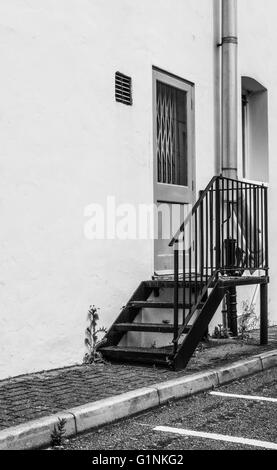 Porta tagliafuoco chiusa a chiave, vista sul lato dell'ingresso di una fabbrica con tubo appena installato visibile. Foto Stock