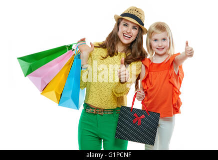 Colorato vibes della famiglia shopping. Ritratto di felice madre e figlia con le borse della spesa su sfondo bianco che mostra i pollici Foto Stock