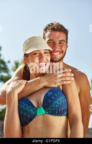 Coppia in vacanza in spiaggia che abbraccia ogni altra felicemente Foto Stock