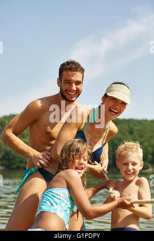 Famiglia felicemente sorridente e riproduzione di rimorchiatore di guerra in un team sulla loro vacanza Foto Stock