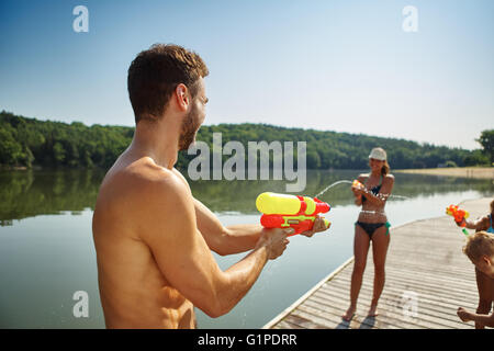 Famiglia avente il divertimento e la spruzzatura di ogni altro con squirt pistole in estate Foto Stock