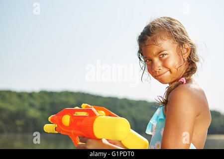 Ragazza che gioca con una pistola spruzza sulle vacanze estive Foto Stock