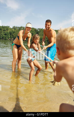 Famiglia giocando rimorchiatore di guerra a Lago d'estate Foto Stock